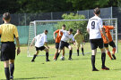 Mehrere Spieler auf einem Fußballfeld mit Tor im Hintergrund.