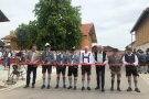 Mehrere Personen in Tracht (Gemeindevertreter und die Landrätin) stehen auf einer Straße und schneiden ein Band zur Eröffnung durch. 