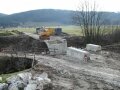 Baustelle mit Bagger vor Wiesen und Wald