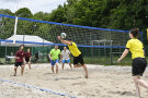 Mehrere Spieler auf einem Volleballfeld. Einer davon boxt den Ball nach oben.