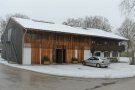 Ein Gebäude mit teilweiser Holzfassade von außen im Winter.