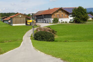 Im Hintergrund ein Bauernhof auf den eine neue Straße zuführt.