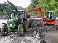 Bagger und Landmaschine beim Ausbaggern eines Sees.