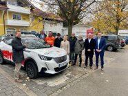 Gruppe von Leuten steht um einen Pkw