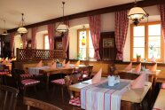 Eine Gaststube in einem bayerischen Wirtshaus mit rot karierten Vorhängen.