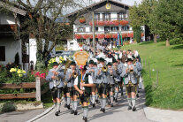 Personen in Tracht beim Festumzug. Voran geht eine Blasmusikkapelle.