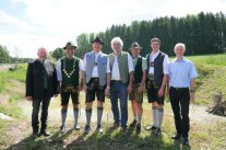 Mehrere Personen, zum Teil in Tracht, stehen draußen für ein Gruppenfoto nebeneinander. 