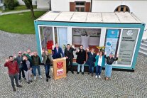 Personengruppe vor einem gläsernen Container