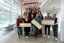 Ein Gruppenbild von Studierenden auf einer Treppe, die Modelle in der Hand halten.