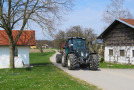 Auf der neuen landwirtschaftlichen Erschließungsstraße fährt ein schwerer Traktor mit Holzabfuhrwagen.