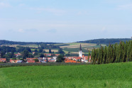 Ein Dorf in der Hallertau wird von einem Hopfengarten eingerahmt. Im Hintergrund die abwechslungsreiche Kulturlandschaft im tertiären Hügelland.  